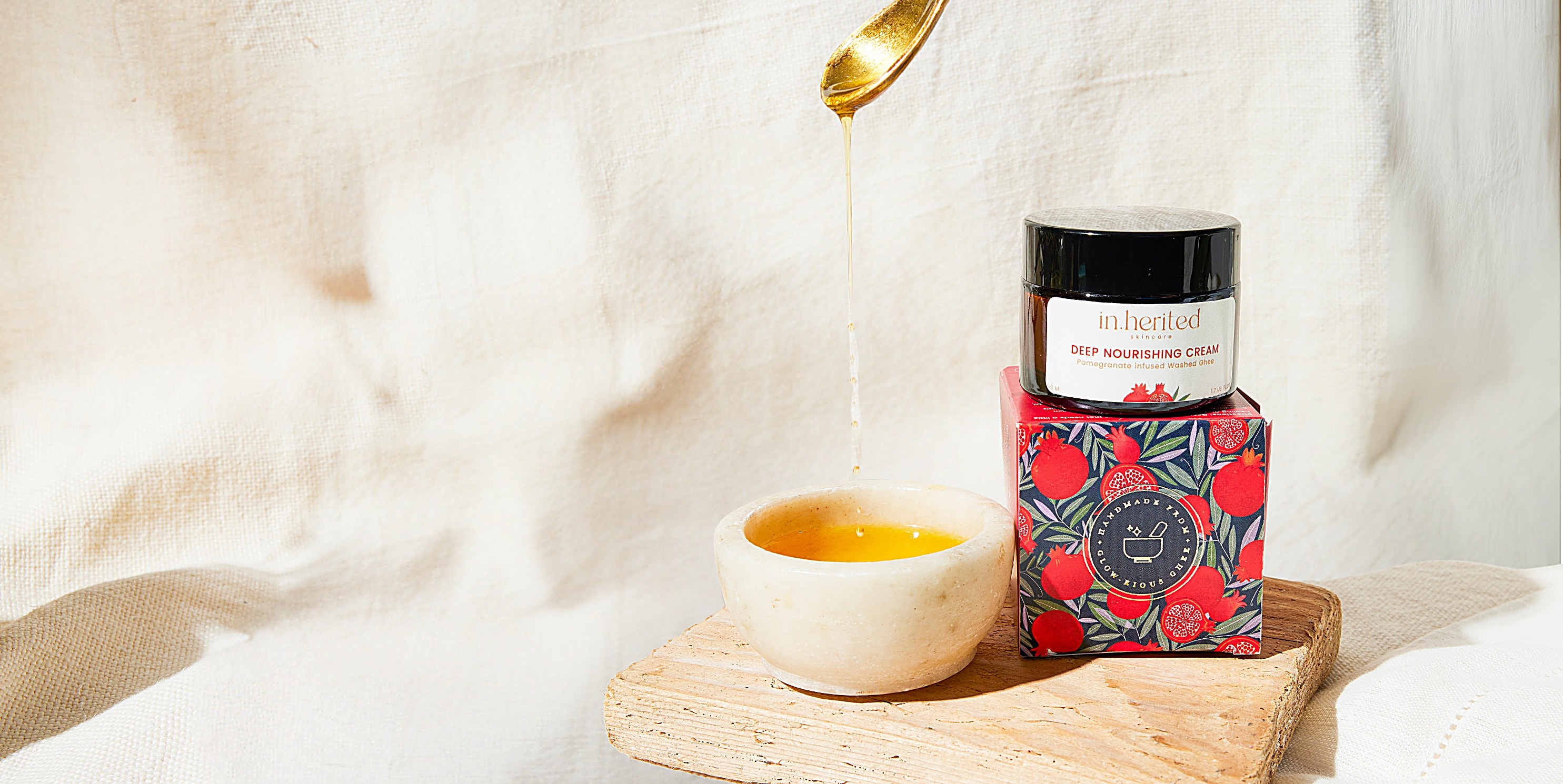 Warm ghee poured into a marble bowl beside the Deep Nourishing Cream on its pomegranate box